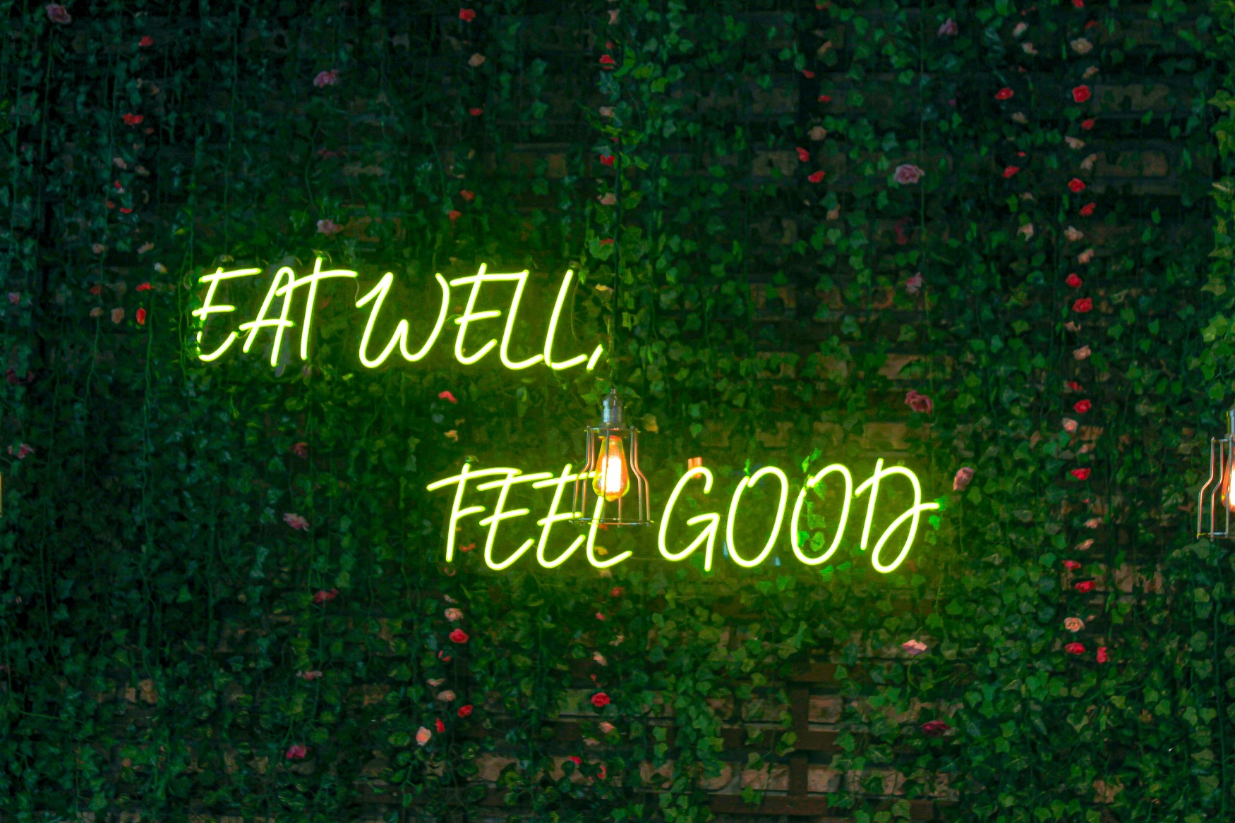 Ein Neon-Schriftzug "Eat Well, Feel Good" vor dunklem Hintergrund