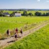 Eine vierköpfige Familie wandert im Sonnenschein über einen Feldweg im Bergischen Land