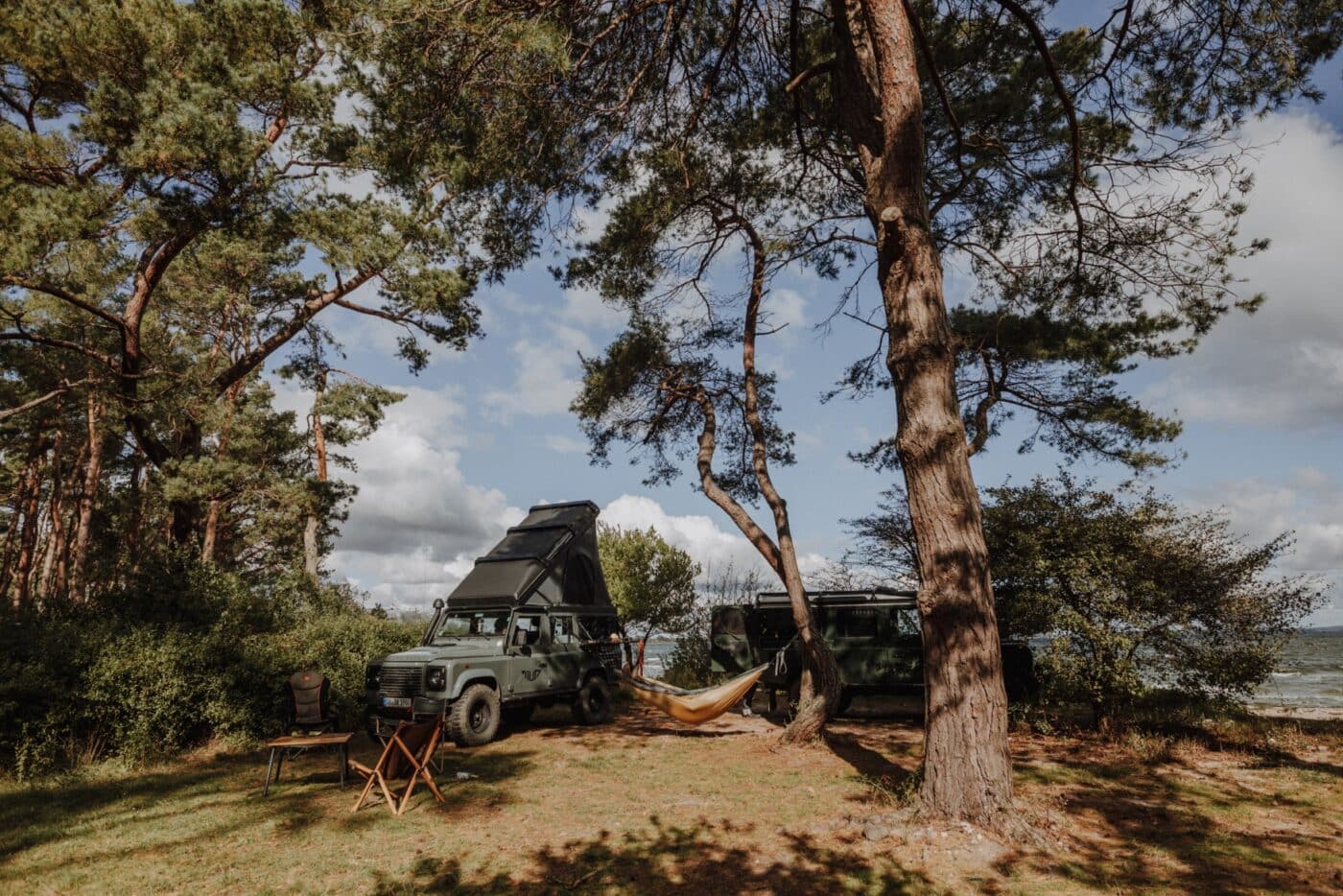 Ein Camperjeep auf einem Strand auf Rügen, daneben eine Hängematte