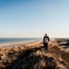 Eine Frau in Wanderkleidung steht auf einer Düne an der Nordsee