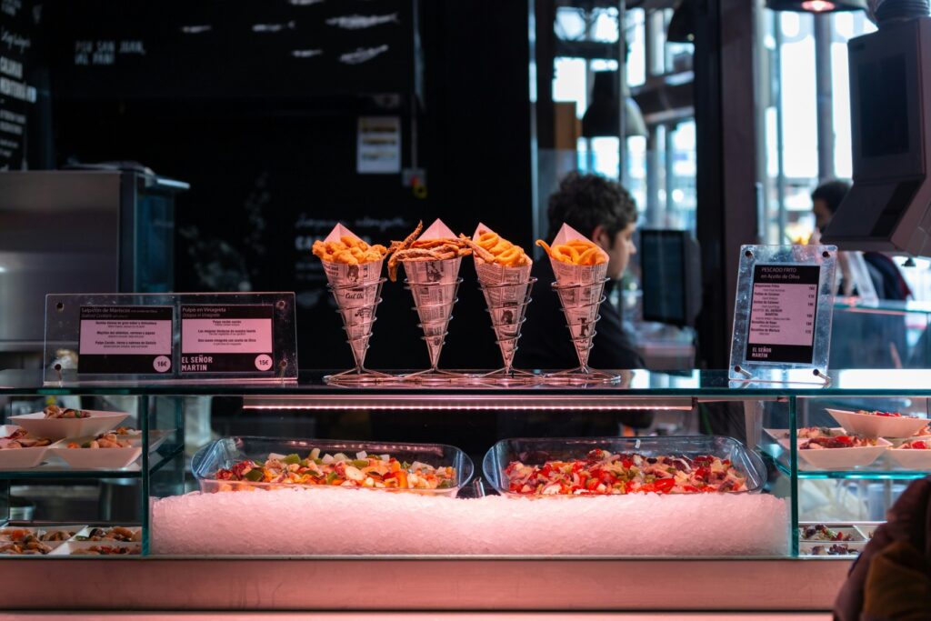 A counter with four portions of fries in bags on it