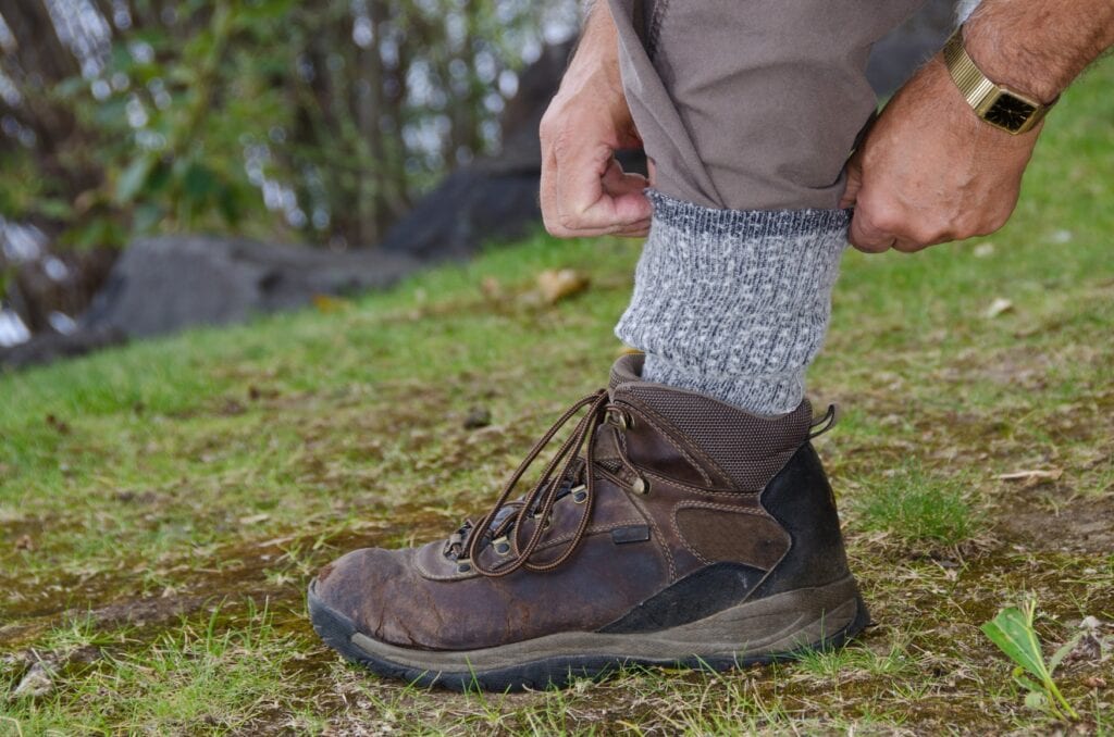 Eine Person stopft ihr Hosenbein in den Bund ihrer Wandersocken