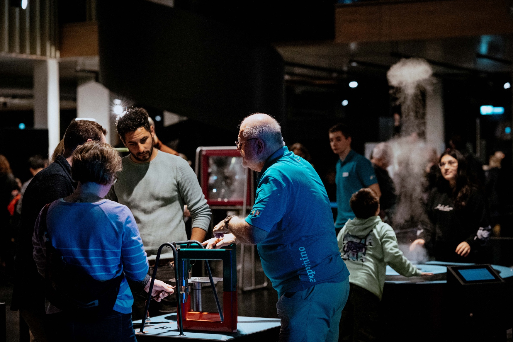 Mehrere Personen stehen in einem nächtlichen Museum um angestrahlte Technik-Exponate herum