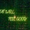 Neon lettering “Eat Well, Feel Good” on a dark background