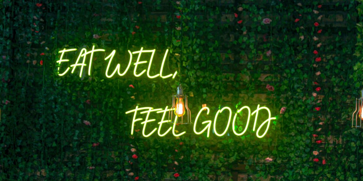 Neon lettering “Eat Well, Feel Good” on a dark background