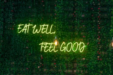 Neon lettering “Eat Well, Feel Good” on a dark background