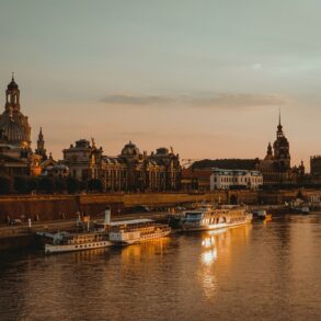 Die Dächer der Dresdner Altstadt, mit Landtag und Frauenkirche, liegen am Elbufer im roten Licht der Abendsonne.