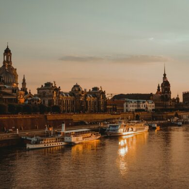 Die Dächer der Dresdner Altstadt, mit Landtag und Frauenkirche, liegen am Elbufer im roten Licht der Abendsonne.