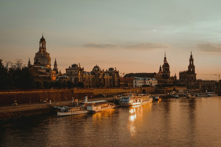 Die Dächer der Dresdner Altstadt, mit Landtag und Frauenkirche, liegen am Elbufer im roten Licht der Abendsonne.