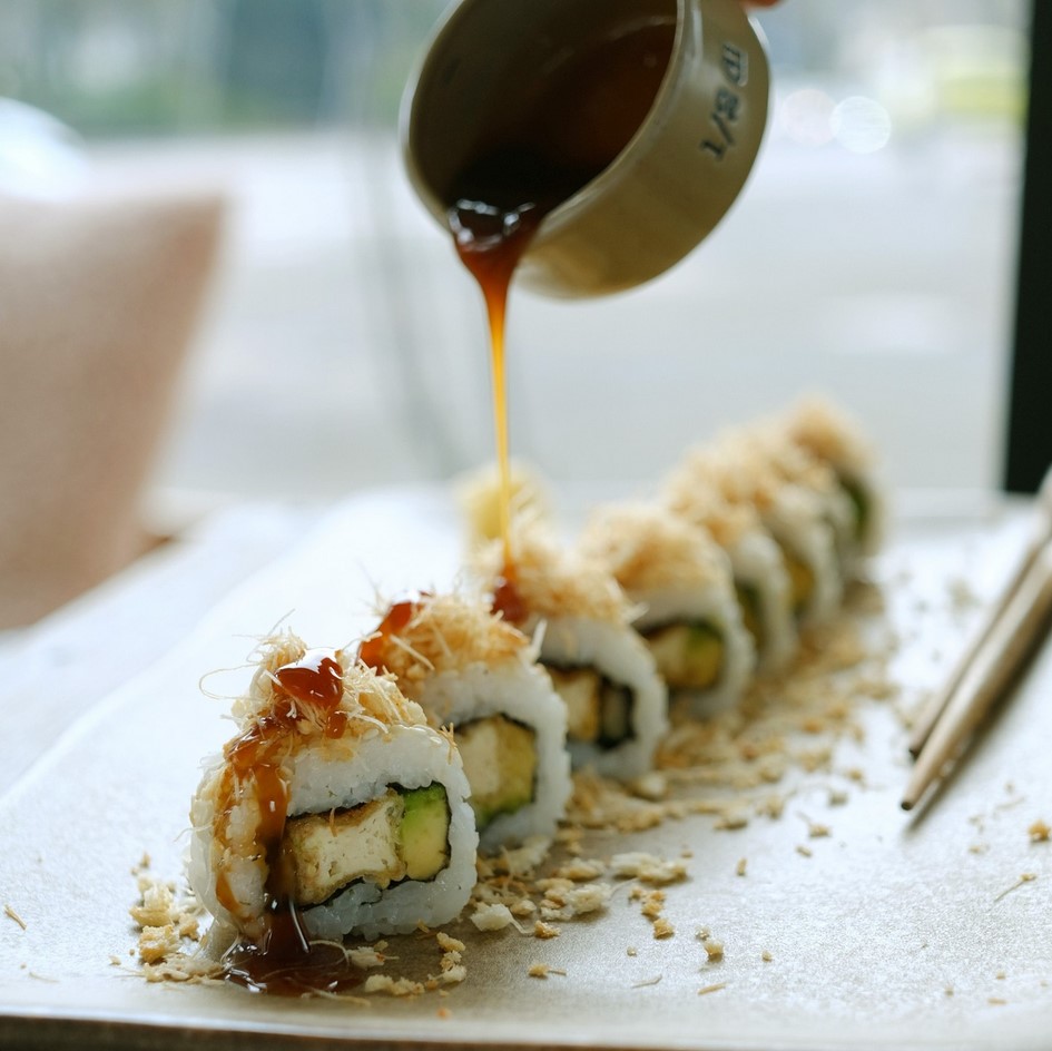 A selection of vegan maki rolls topped with sauce