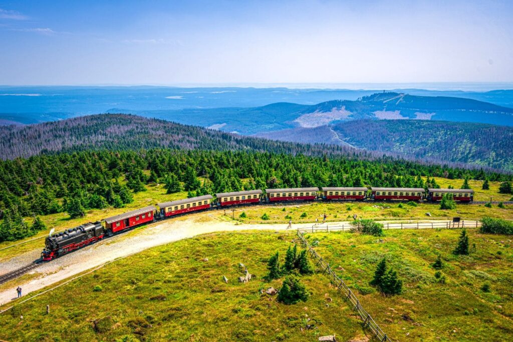 The Brocken Railway travels over a hill in the Harz National Park in bright sunshine.