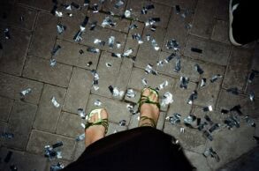 Ein Paar Füße in grün-glänzenden High-Heels stehen auf Pflastersteinen, rundherum silbernes Konfetti. Das Foto sieht aus, wie von der Fußinhaberin selbst fotografiert.