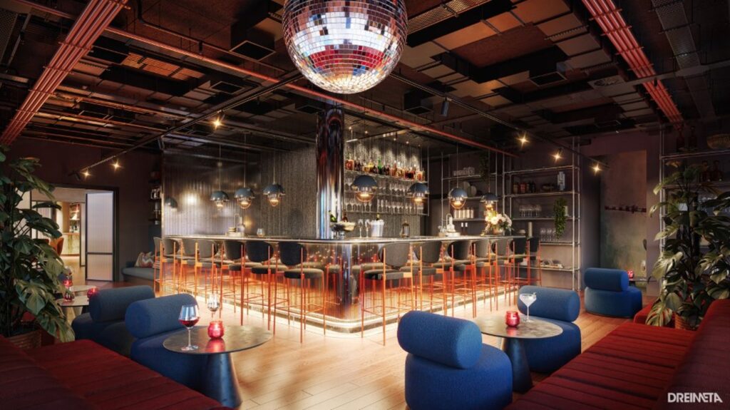 Ein Bar- und Loungebereich in einem Hotel. Um eine L-förmige Bar in der Mitte sind mehrere Hocker aufgestellt. Auf der jeweils gegenüberliegenden Seite sind kleine Sitzgruppen mit einer roten Polsterbank und jeweils zwei blauen, modernen Polstersessel. Die Decke des Raums ist im Industrial-Stil ohne Verkleidung, von der Decke hängt eine riesige Discokugel. Auch die Bar selbst ist mit glänzenden Pailletten verkleidet.