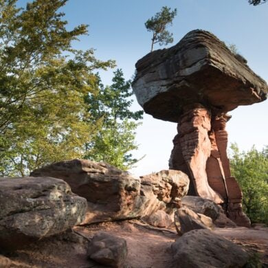 Auf einer roten Sandsteinsäule ruht ein riesiger Sandsteinquader; ein wenig sieht die Formation aus wie ein Tisch. Rundum weitere Sandsteinfelsen, der Himmel darüber blau