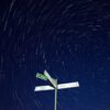 Ein Wegweiser für Fußgänger vor dem Hintergrund eines nächtlichen Sternenhimmels; Auf dem Wegweiser sind die Orte Strodehne, Gahlberg und der Gülper See verzeichnet