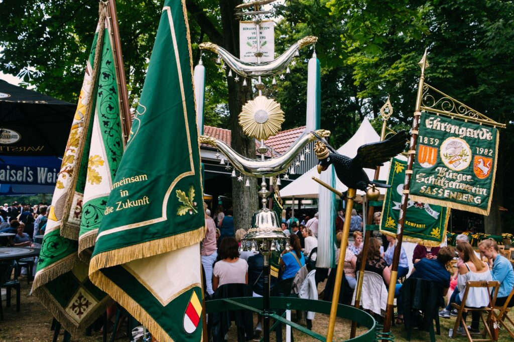 A row of green and golden banners of german shooting clubs.
