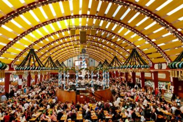 Panoramic view of a festival tent at Oktoberfest in Munich. Every table is full of people.