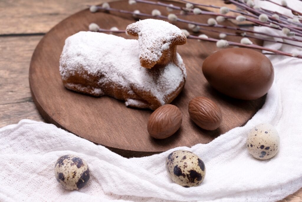 Auf einem runden Brettchen liegt ein mit Puderzucker bestäubtes Osterlamm.