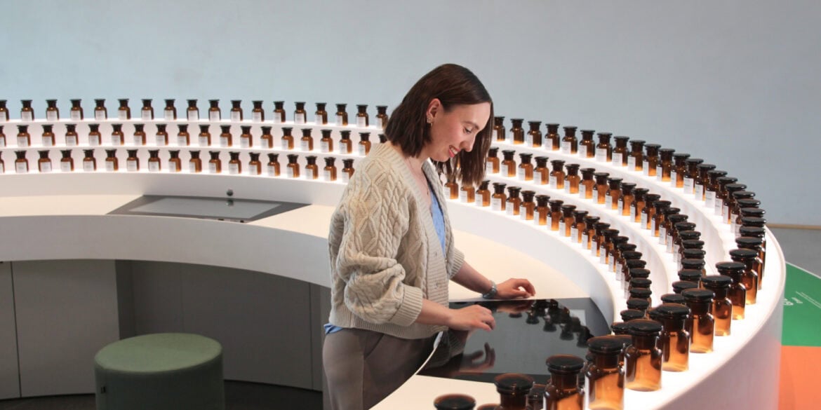 A young woman is operating a touchscreen built into a semicircular sideboard. Along the outer edge of the sideboard are