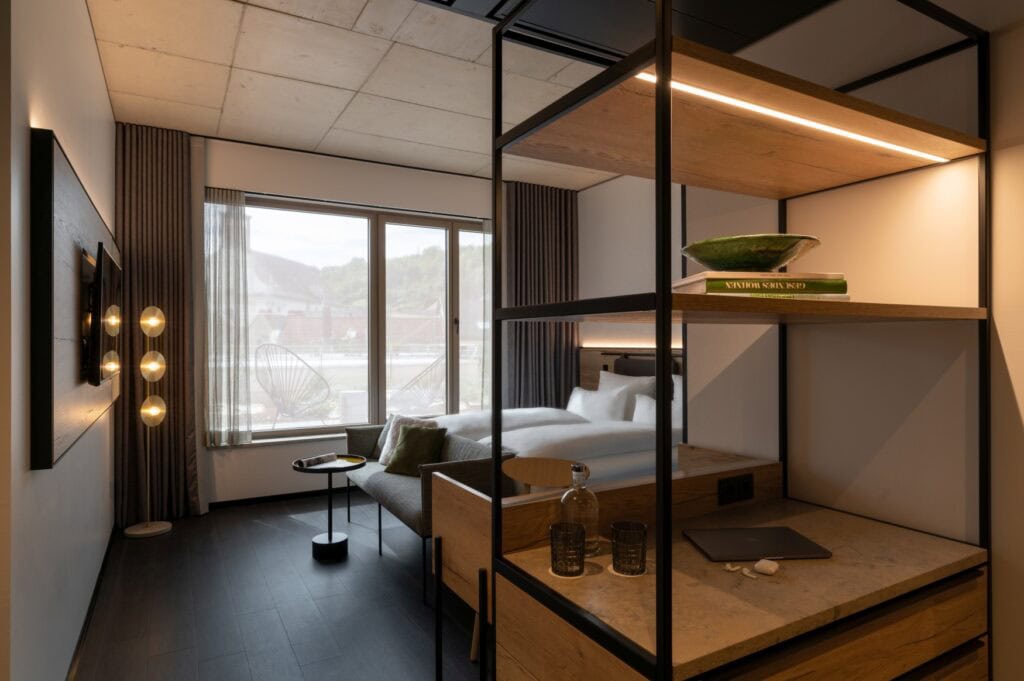 Ein Hotel Zimmer im Hotel "Das Altmühltal" in Eichstätt, mit dunklem Holzfußboden, einem offenen Regal als Raumtrenner, einem Doppelbett und einem Ausblick auf die Stadt.