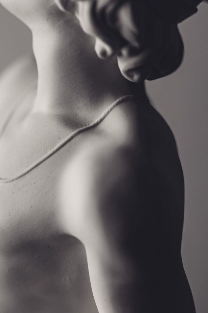 Detailaufnahme der nackten Schulter einer Porzellanfigur.