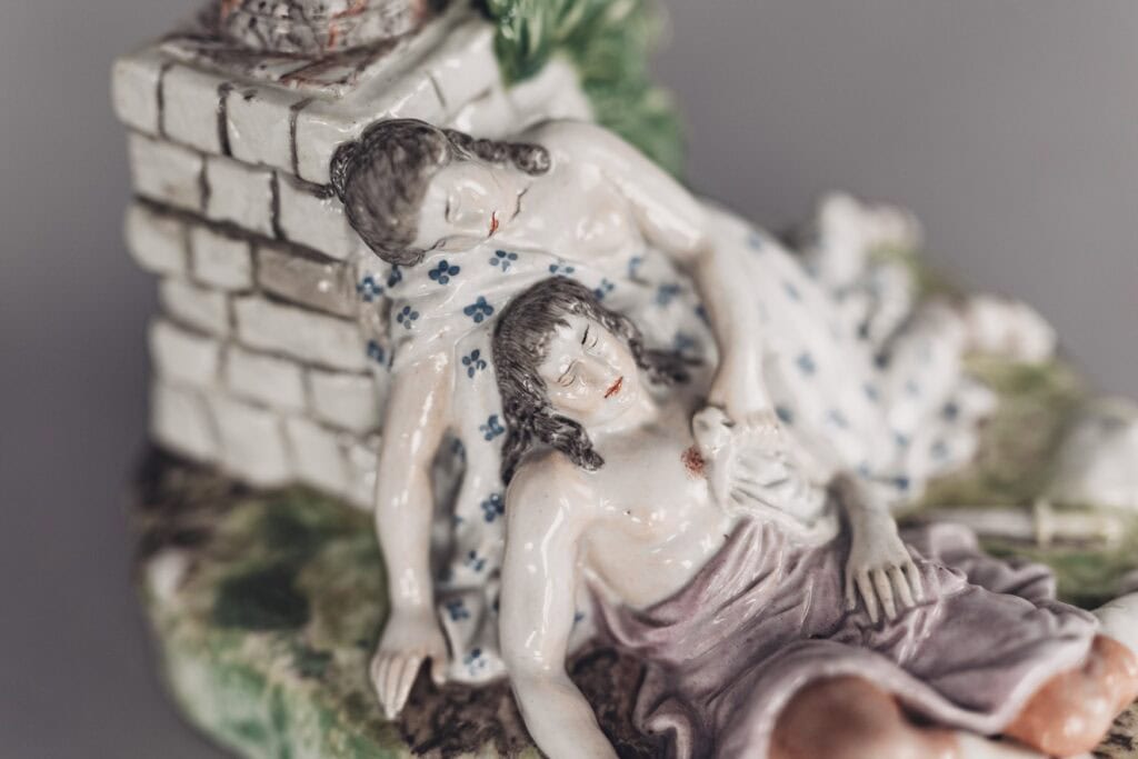 Detailaufnahme einer Porzellanfigur, die eine Schäferszene an einem kleinen Mäuerchen zeigt.