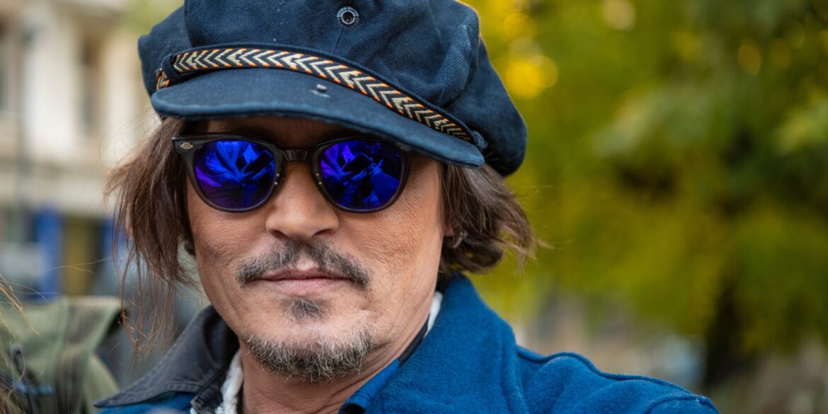 Der Schauspieler Johnny Depp mit einer blauen Mütze, einer blau getönten Sonnenbrille und einer blauen Jacke.