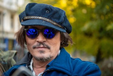 Der Schauspieler Johnny Depp mit einer blauen Mütze, einer blau getönten Sonnenbrille und einer blauen Jacke.