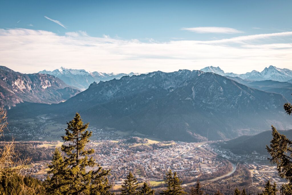 A view from a lookout point of the town of Bad Reichenhall in the valley, with a sweeping Alpine panorama unfolding behind it.