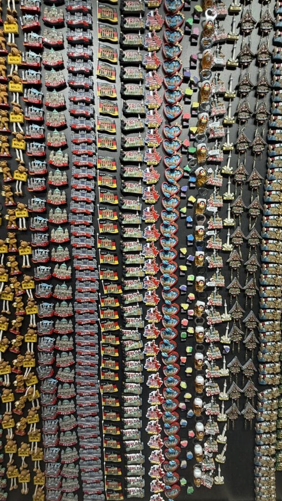 Auf einer schwarzen Wand sind zahlreiche Souvenir-Kühlschrankmagnete aus Berlin angebracht.