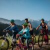 Zwei Kinder fahren mit ihren Eltern auf Fahrrädern einen Feldweg entlang, im Hintergrund sieht man einen Wald und eine Gipfelkette der Alpen bei Garmisch-Partenkirchen