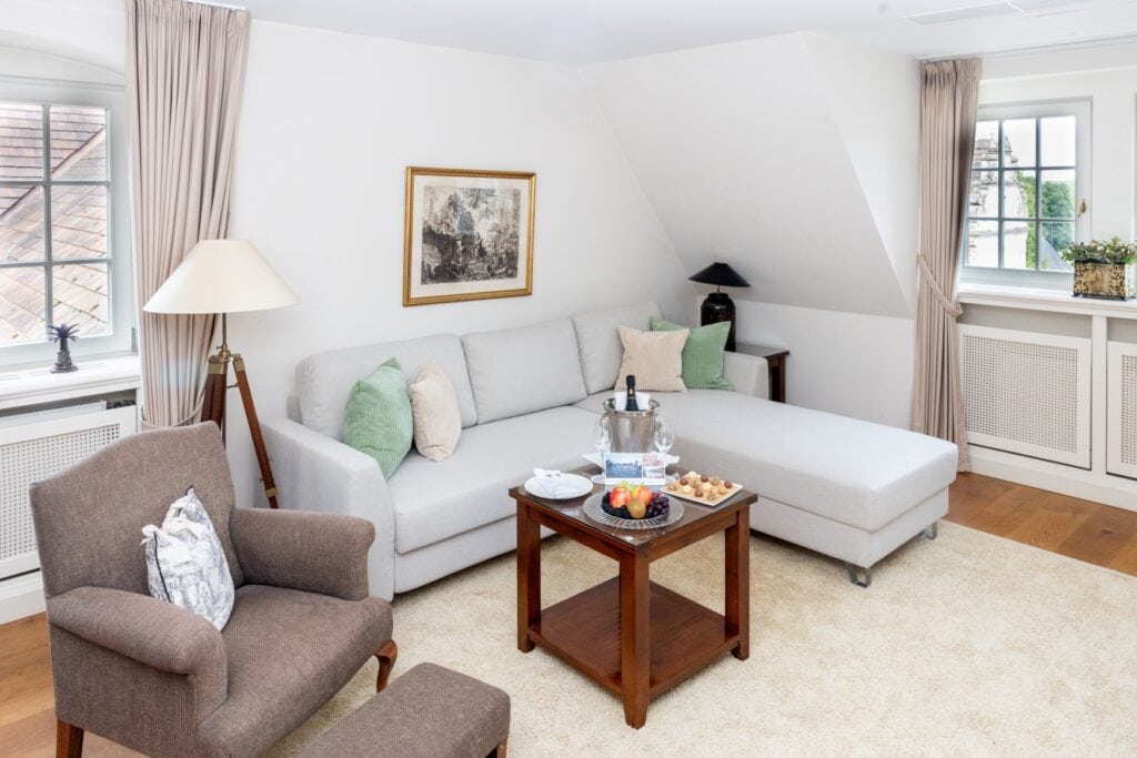 Sitzecke in einer Suite im Schlosshotel Münchhausen, mit einem grau gepolsterten Ecksofa.