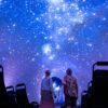 Zwei Personen schauen im Planetarium in Jena an den projizierten Nachthimmel in der Kuppel