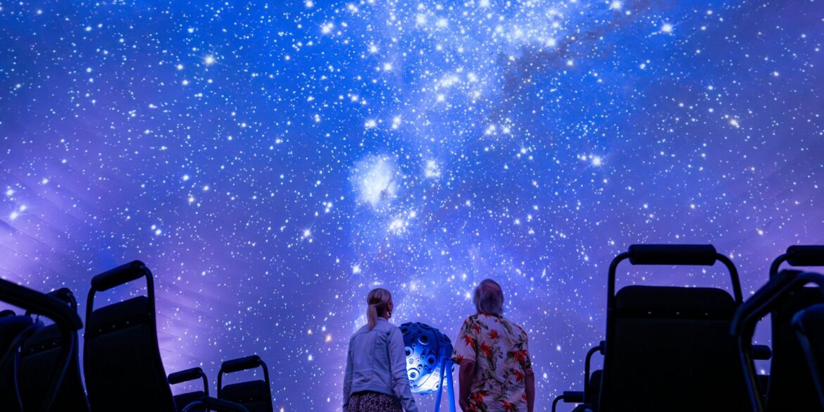 Zwei Personen schauen im Planetarium in Jena an den projizierten Nachthimmel in der Kuppel