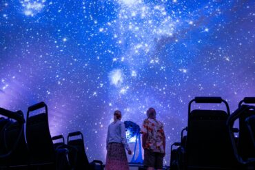 Zwei Personen schauen im Planetarium in Jena an den projizierten Nachthimmel in der Kuppel