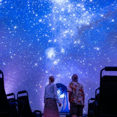 Zwei Personen schauen im Planetarium in Jena an den projizierten Nachthimmel in der Kuppel