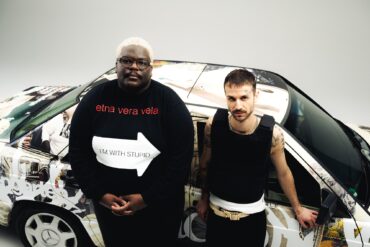The german duo "Blumengarten" at a video shooting, standing in front of a car painted with graffiti