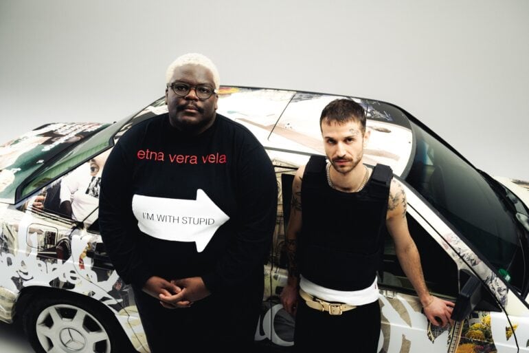 The german duo "Blumengarten" at a video shooting, standing in front of a car painted with graffiti