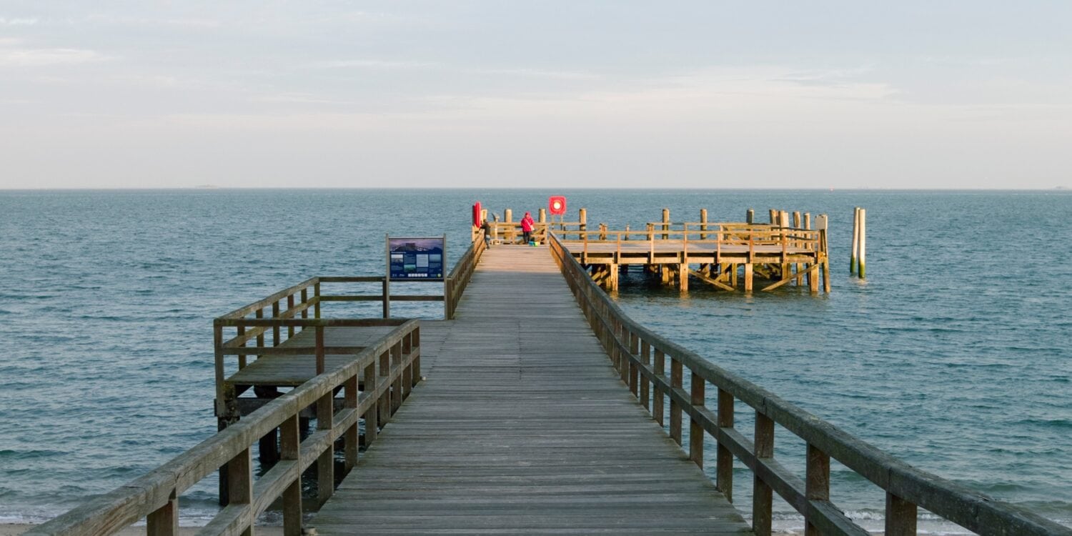 Ein hölzerner Steg auf der Insel Föhr führt auf die Nordsee hinaus.