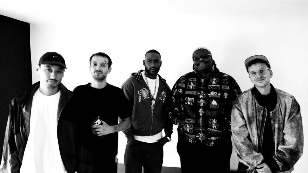 Schwarzweißes Pressefoto zur Single „Gut Genug": fünf Beteiligte des Tracks stehen in einer Reihe vor einer hellen Wand und schauen in die Kamera.