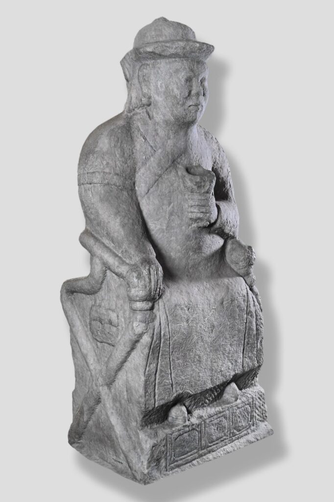 Steinstatue eines mongolischen Würdenträgers aus dem Gräberfeld Tavan Tolgoi, 13. bis 14. Jahrhundert. Die sitzende Figur trägt eine flache Kappe und ein gegürtetes Gewand, in der rechten Hand hält sie ein Gefäß, an der linken Seite hängt ein Köcher.