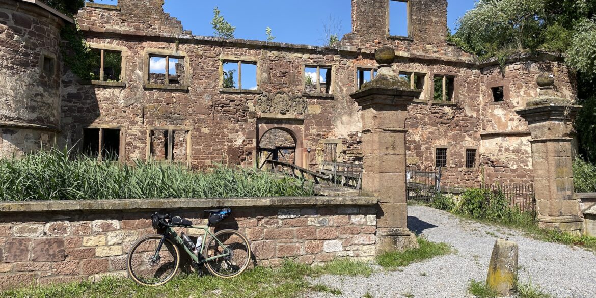 Lost Places in Baden-Württemberg: Ruine des Wasserschlosses Menzingen in Kraichtal mit verwitterten Steinmauern, leeren Fensteröffnungen und einem Fahrrad im Vordergrund.