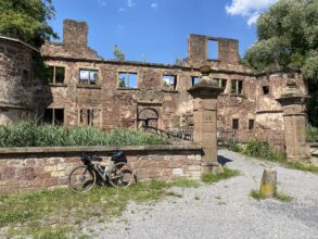 Lost Places in Baden-Württemberg: Ruine des Wasserschlosses Menzingen in Kraichtal mit verwitterten Steinmauern, leeren Fensteröffnungen und einem Fahrrad im Vordergrund.