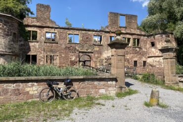 Lost Places in Baden-Württemberg: Ruine des Wasserschlosses Menzingen in Kraichtal mit verwitterten Steinmauern, leeren Fensteröffnungen und einem Fahrrad im Vordergrund.