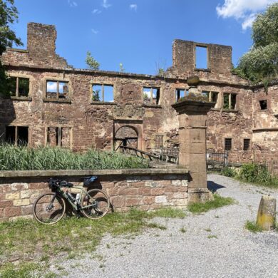 Lost Places in Baden-Württemberg: Ruine des Wasserschlosses Menzingen in Kraichtal mit verwitterten Steinmauern, leeren Fensteröffnungen und einem Fahrrad im Vordergrund.